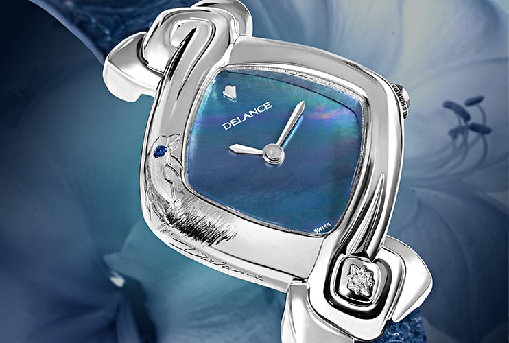 Un charmant dauphin sortant des eaux est gravé artistiquement sur le côté de cette montre DELANCE "Dolphin". Il semble vouloir plonger dans les vagues bleues irisés du cadran de nacre. Toute de pureté et de simplicité elle signifie, pour la personne qui la porte, son amour de la nature et de la mer. : Montre en acier, cadran nacre bleue, aiguilles nickelées, cabochon en acier avec un diamant à 6h, bracelet en alligator bleu